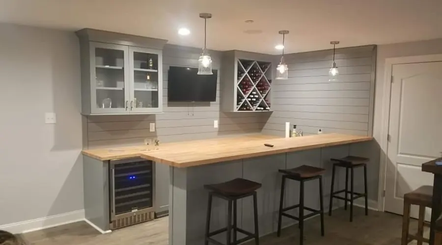Custom basement bar with wine rack, pendant lights, and long countertop