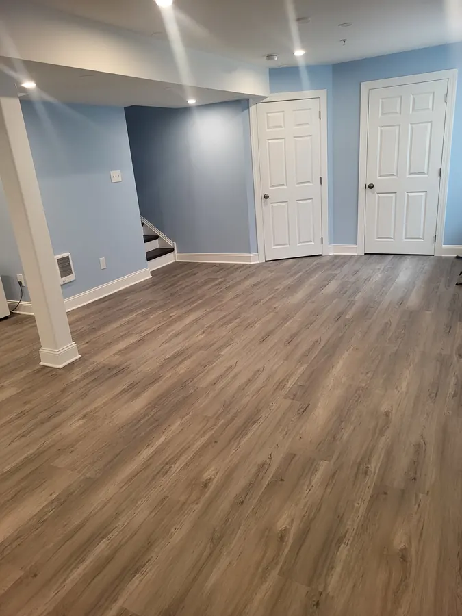 Finished basement with blue walls, white doors, and wood-look flooring